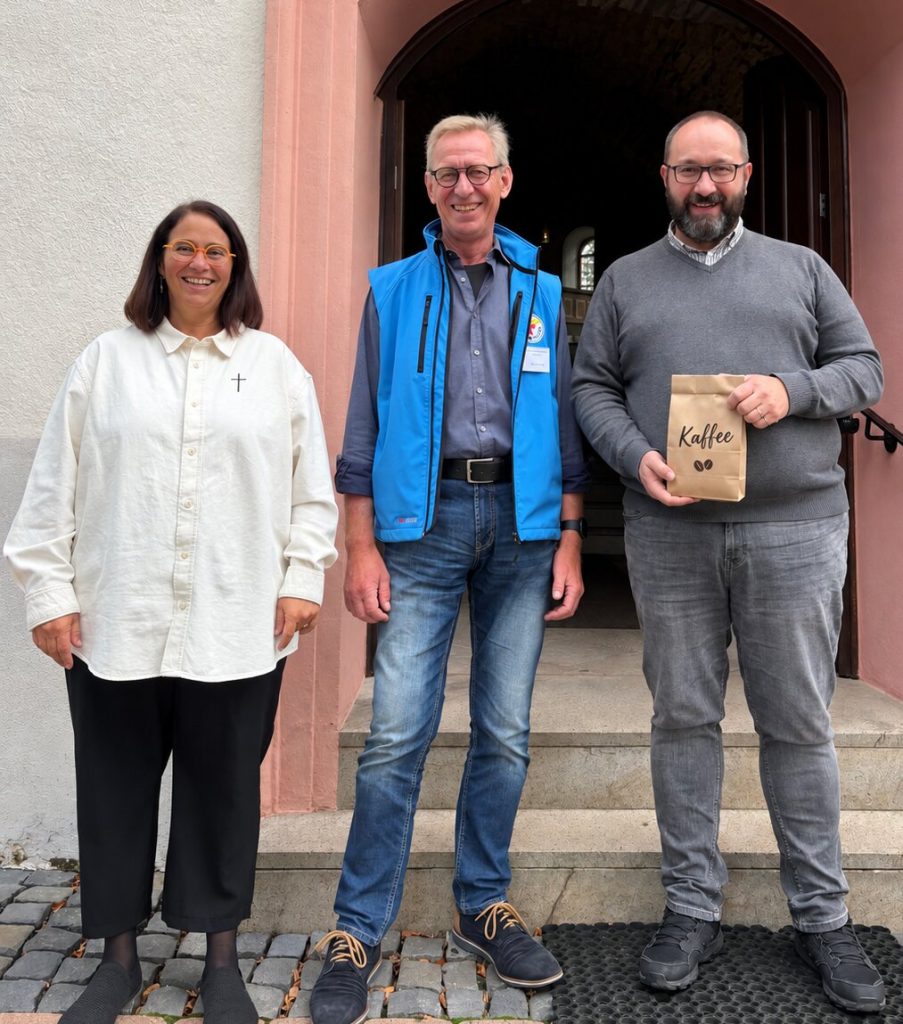 Gemeinsam für „Eine Tasse Menschlichkeit“: Thorsten Bienemann (rechts), Männerbeauftragter des Evangelischen Kirchenkreises Altenkirchen und Initiator der Spendenaktion, mit Günter Papst (Mitte), Leiter der Bahnhofsmission Koblenz, und Nicole Eker, Pfarrerin der Evangelischen Kirchengemeinde Daaden, beim Erntedankgottesdienst in Daaden. Papst stellte dort die Arbeit der Bahnhofsmission vor und warb gemeinsam mit Bienemann um Unterstützung für die Kaffeesammlung. Foto: © Thorsten Bienemann